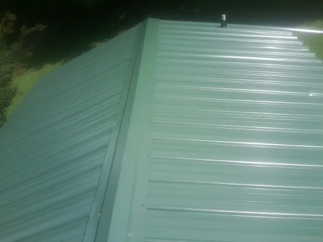 New green metal panels meeting at the ridge of a roof — Flat Roof Repair work by our crew in Kingsland