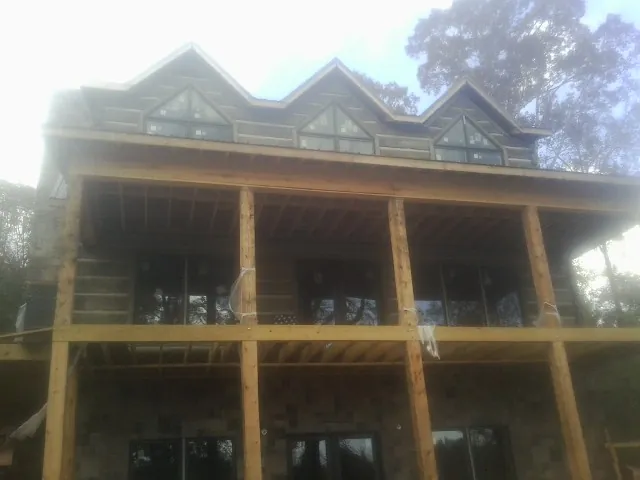 Dormers and porch framing on a large log home under construction — Roof Coating work by our crew in Kingsland