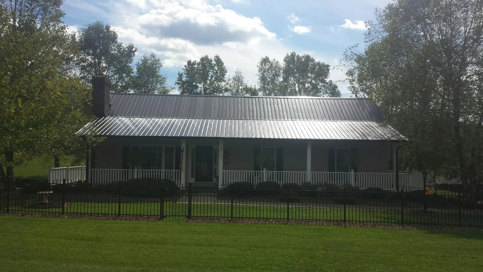 Gray metal roof on a brick ranch with a full width front porch — Gutter Guard Installation work by our crew in Kingsland